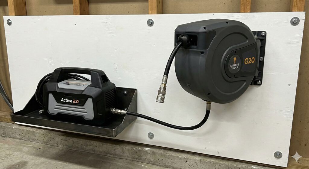 A wall-mounted Active 2.0 pressure washer and Giraffe Tools retractable reel installed securely on a plywood backer board.